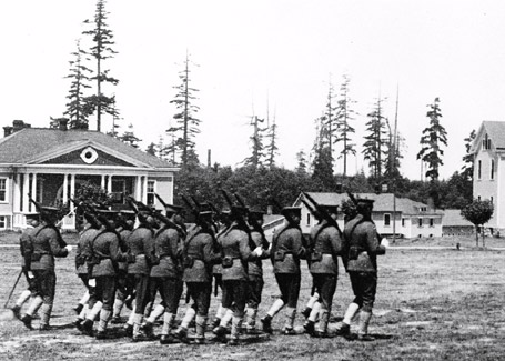  A squad of troops marching past the Post Exchange and Gymnasium  on the Fort Lawton parade ground. These soldiers are wearing the  standard service uniform issued circa 1903. Photo by Asahel Curtis.  Seattle Department of Parks and Recreation, Discovery Park Photographic  Archive, Photographer’s File #U-3, a portion of 14734. Circa 1909. 